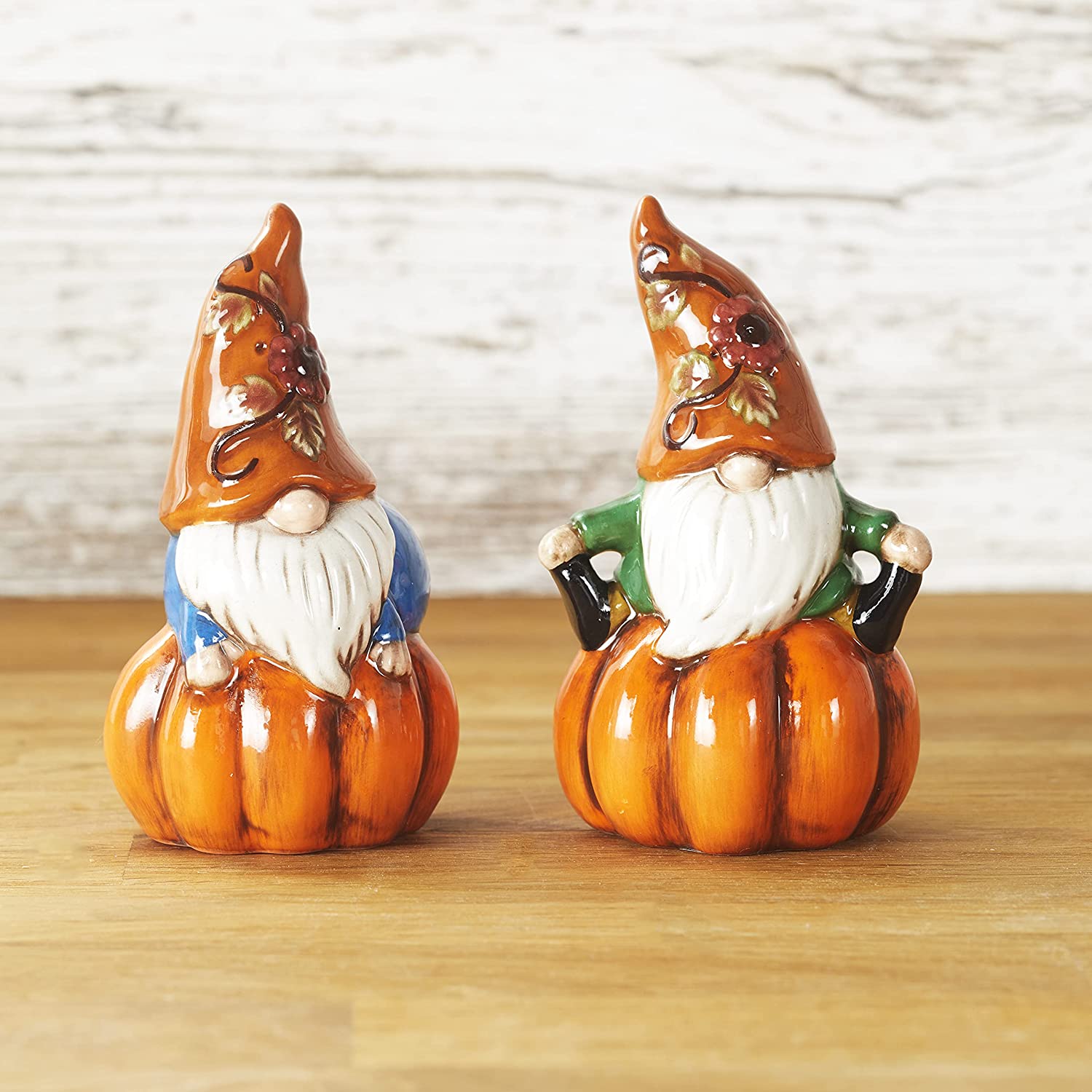 Ceramic figurines of gnomes perched on a pumpkin and wearing a harvest orange hat.