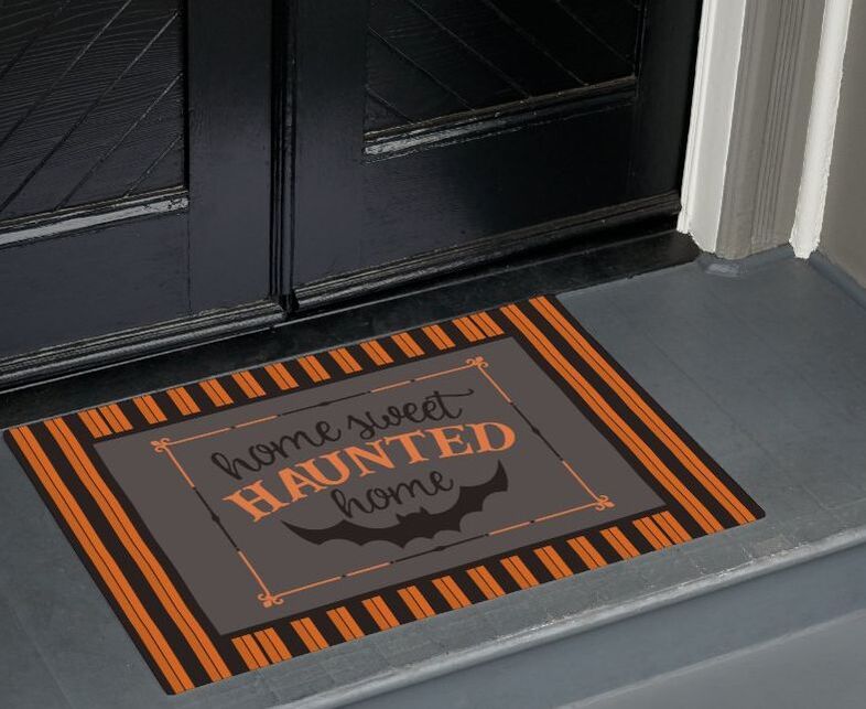 Halloween doormat featuring bold orange and black striped background with center Home Sweet Haunted Home text